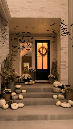 a set of steps leading up to a front door decorated with pumpkins and bats