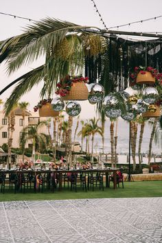 an outdoor dining area with palm trees and hanging decorations