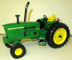 a green toy tractor sitting on top of a white floor