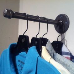 three shirts hanging on a rail in front of a wall with a coat hanger