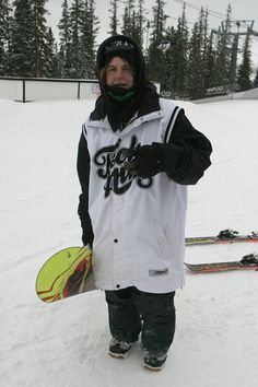 a man standing in the snow with his snowboard