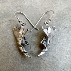 "One pair of rat jaw earrings, available in brass ($69) or sterling silver ($89). These jaws have a story. A friend in southern Arizona has a pair of great horned owls as neighbors. These owls perch on their home and trees regularly, and leave owl pellets all over the land. For those who don't know, owl pellets are the undigested parts of the bird's food, such as hair or bones, which are regurgitated (coughed up through the beak). There is often a full mouse or rat skull in each owl pellet, along with all the other little bones. So, of course I wanted to dissect an owl pellet to see what treasures I could find, hah! These jawbones are something I found inside. Once I had the original forms, I made molds and cast them in metal. These jaw pieces are a mirror image match (they are from the sa Animal Bone Jewelry Clay, Rat Skull, Owl Pellet, Owl Pellets, Bird Skull Jewelry, Southern Arizona, Bone Earrings, Halloween Makeup Inspiration, Jaw Bone