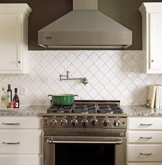 a stove top oven sitting inside of a kitchen next to white cabinets and counter tops