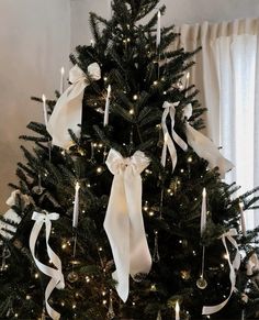 a decorated christmas tree with white ribbons and lights