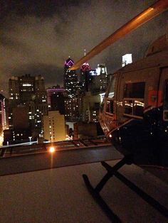 a helicopter that is sitting on the ground in front of a cityscape at night