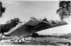 an old black and white photo of people laying on top of a large object in the air