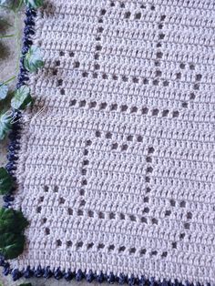 a crocheted blanket with blue trim on the edge and green leaves around it