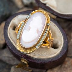 This shell cameo ring is crafted in 10k yellow gold and features a bezel set cameo decorated with seed pearl accents and engraved shoulders. The ring is currently a size 3 and we offer free resizing. The seed pearls are strung on a sturdy copper wire. Victorian Oval Cabochon Pearl Ring, Antique Oval Pearl Ring Stamped 14k, Heirloom Oval Cabochon Pearl Ring, Heirloom Oval Pearl Ring With Cabochon, Fine Jewelry Cameo Wedding Ring, Wedding Yellow Gold Cameo Ring, Fine Jewelry Cameo Oval Rings, Fine Jewelry Cameo Rings For Weddings, Fine Jewelry Cameo Ring For Anniversary