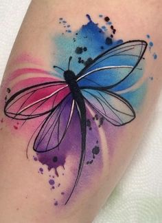 a colorful tattoo with a dragonfly on it's arm and watercolor paint splatters