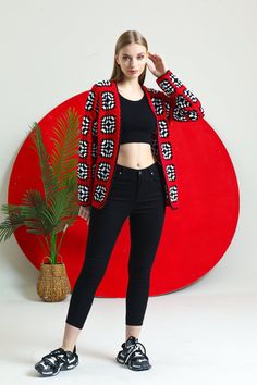 a woman standing in front of a red and white wall with a plant next to her