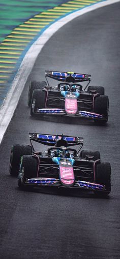 three racing cars on a race track, one is pink and the other is blue