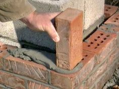 a man is placing bricks into a brick wall