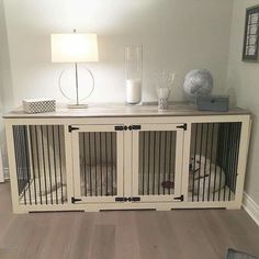 a dog is sitting in his kennel at the end of the room with its door open