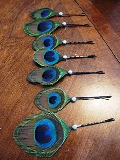 six peacock feathers are lined up on a table with spoons in the shape of an egg