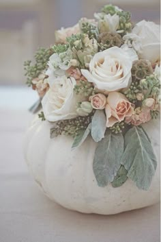 a white pumpkin decorated with flowers and greenery