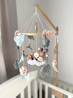 a baby crib mobile with a deer and leaves hanging from it's sides