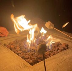 a person is cooking food over an open fire pit with tongs in their hand