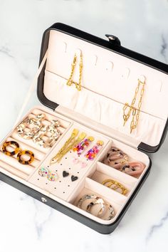 an open suitcase filled with jewelry on top of a white countertop next to a pair of scissors