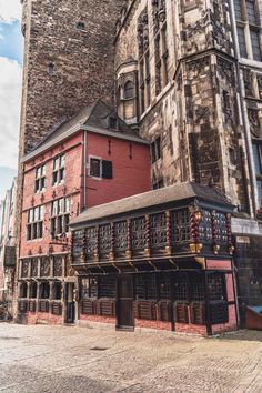 an old brick building in the middle of a cobblestone street next to tall buildings