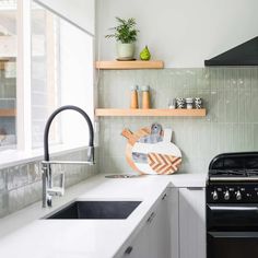 a kitchen with an oven, sink and shelves on the wall next to each other