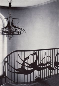 a chandelier hanging from the side of a spiral staircase in a room with white walls