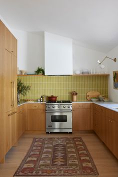 a kitchen with wooden cabinets and an area rug on the floor in front of the stove