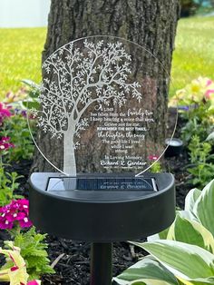 a memorial tree is placed in the middle of a flower garden