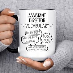 a woman is holding a coffee mug with the words assistant director and dictionary on it