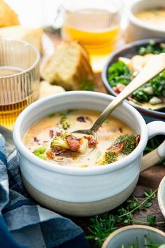 a bowl of soup with broccoli and other foods on the table next to it