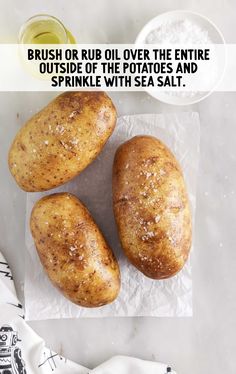 three baked potatoes sitting on top of a piece of paper next to a bowl of salt