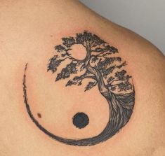 a tattoo on the back of a man's shoulder with a tree and moon