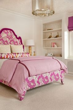 a bedroom with a pink bed and chandelier