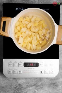 a pot on top of an electric stove with food cooking in it and a digital clock