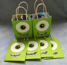 four green bags with monster eyes on them sitting next to each other in front of a gray background