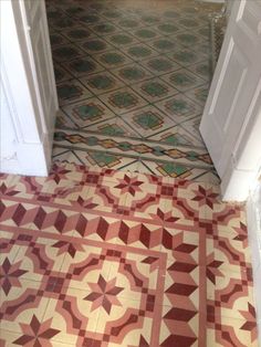 an open door leading to a bathroom with red and green tiles on the floor,