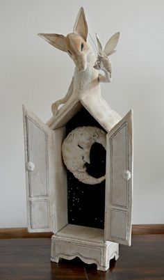 a statue of a fairy sitting on top of a cabinet with a moon in it