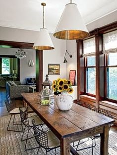 a dining room with sunflowers on the table and two hanging lights above it