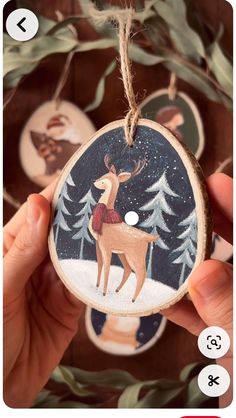 someone is holding up a christmas ornament with deers in the woods on it