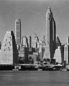 black and white photograph of new york city from across the water, with skyscrapers in the background