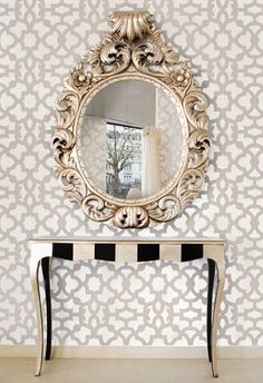 a mirror on the wall next to a table with a black and white striped chair