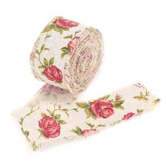 a roll of white and pink floral ribbon with red roses on the side, sitting next to each other