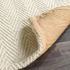 a close up of a white rug on a wooden floor with a tan mat covering it