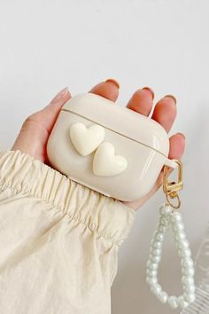 a hand holding a white case with two hearts on it and a keychain