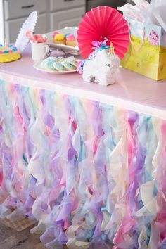 a table topped with lots of cake and cupcakes next to a pink fan