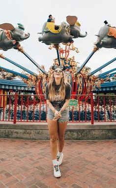 a woman standing in front of a carnival ride