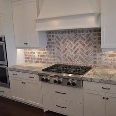 a stove top oven sitting inside of a kitchen next to white cabinets and counter tops