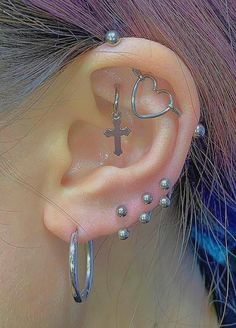 a woman with purple hair wearing ear piercings and a cross on the side of her ear