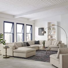 a living room filled with lots of furniture next to large windows and a rug on the floor