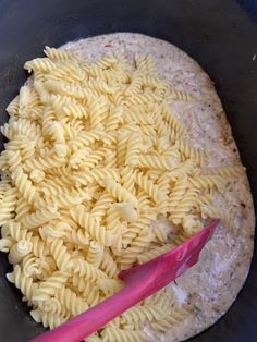 a bowl filled with pasta and a pink spoon