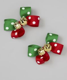 two red, green and white bows with gold bells on each bow are sitting next to each other